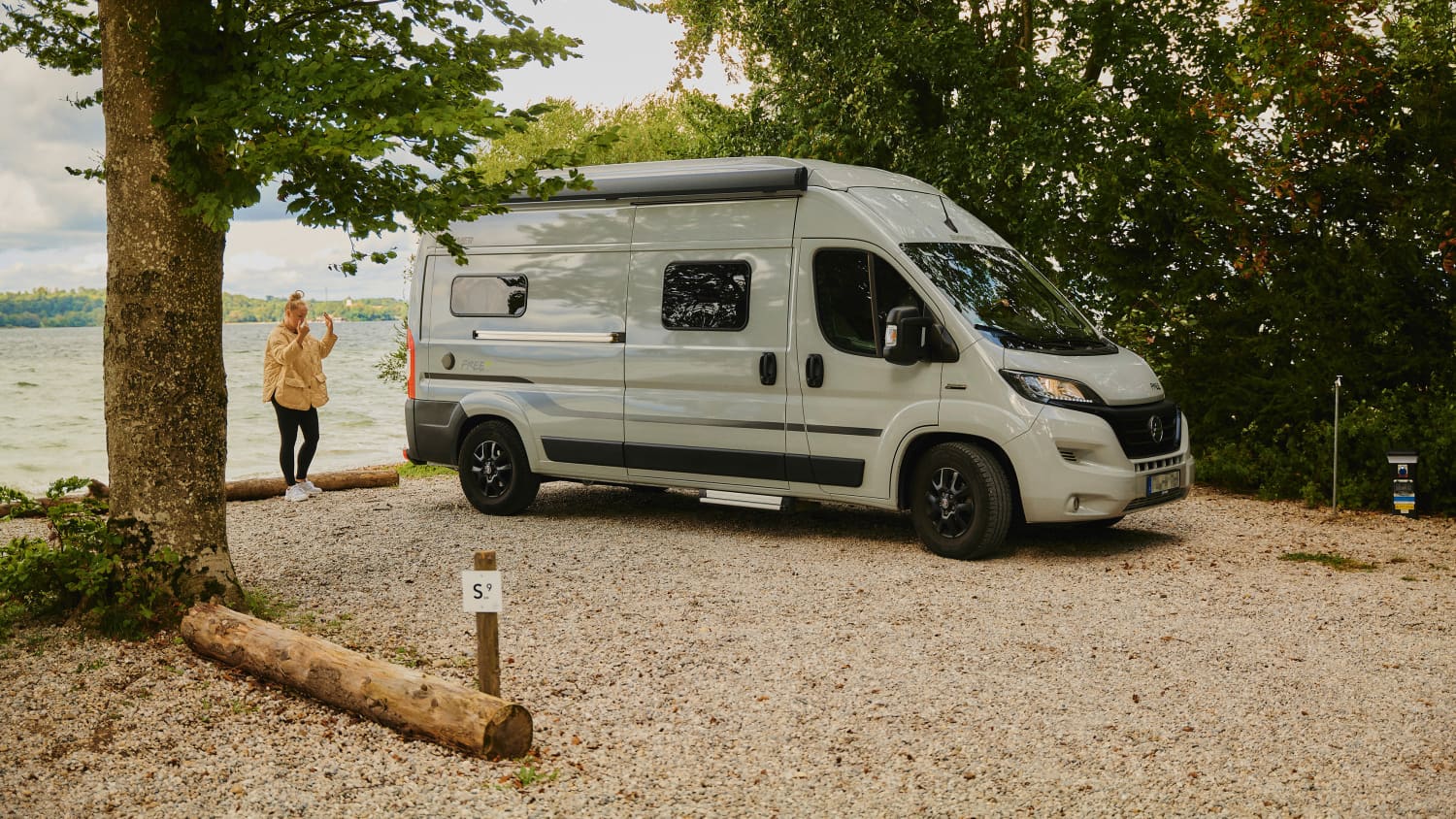 Eine Frau weißt ihren Partner mit dem Wohnmobil auf einen Stellplatz am Campingplatz ein