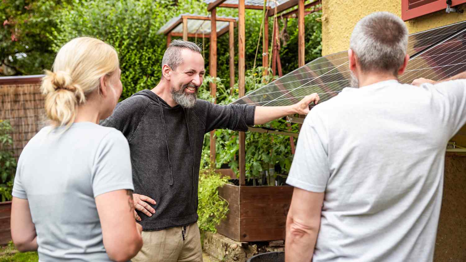 Zwei Männer und eine Frau stehen vor Solarpanelen