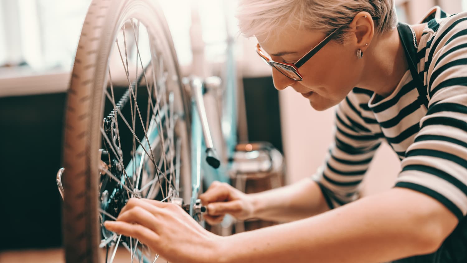 Eine Frau mit kurzen blonden Haaren repariert Ihr Fahrrad