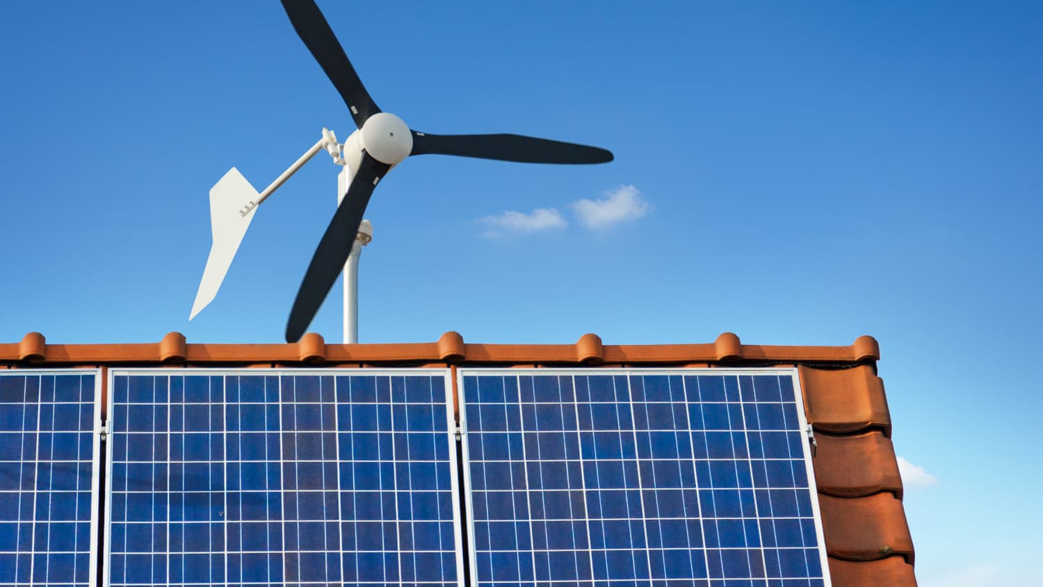 Kleine Windkraftanlage und Sonnenkollektoren auf einem privaten Gebäude