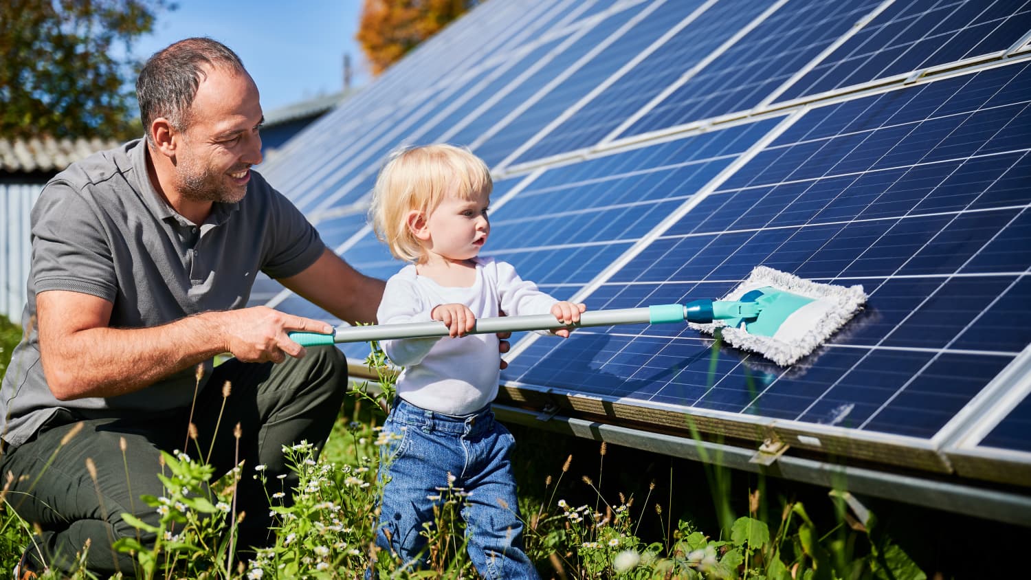 Ein Mann und sein kleiner Sohn reinigen die Photovoltaikanlage