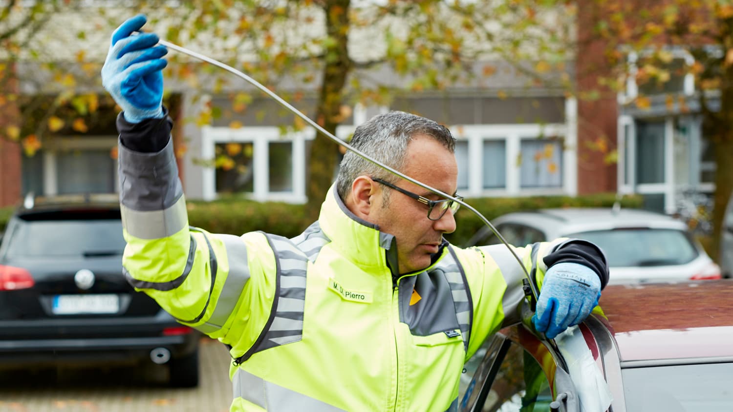 Ein Straßenwachtfahrer versucht mit hilfe eines Drahtes ein verschlossenes Auto zu öffnen