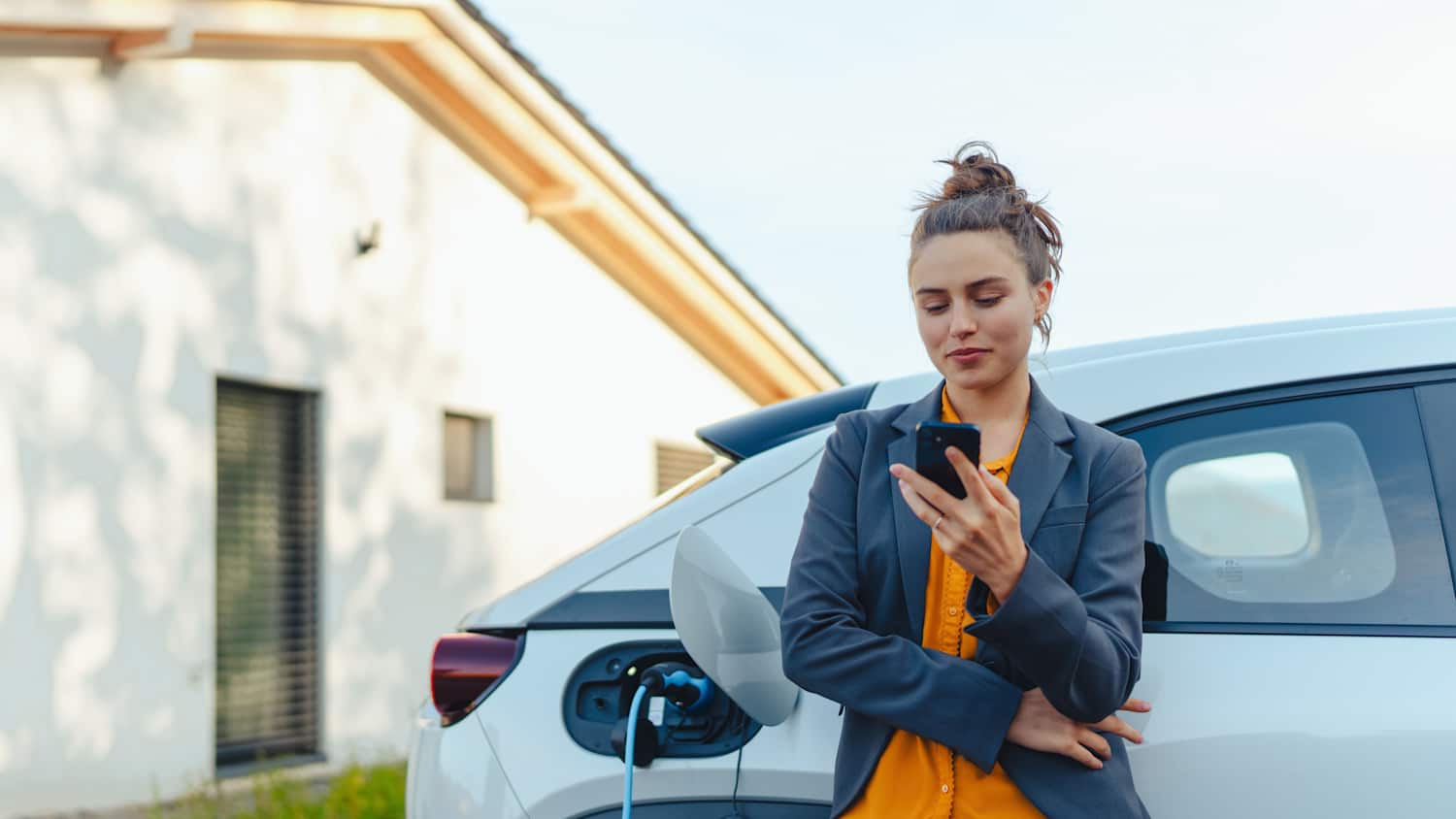 Eine Frau läd ihr Auto via App in ihrem handy auf