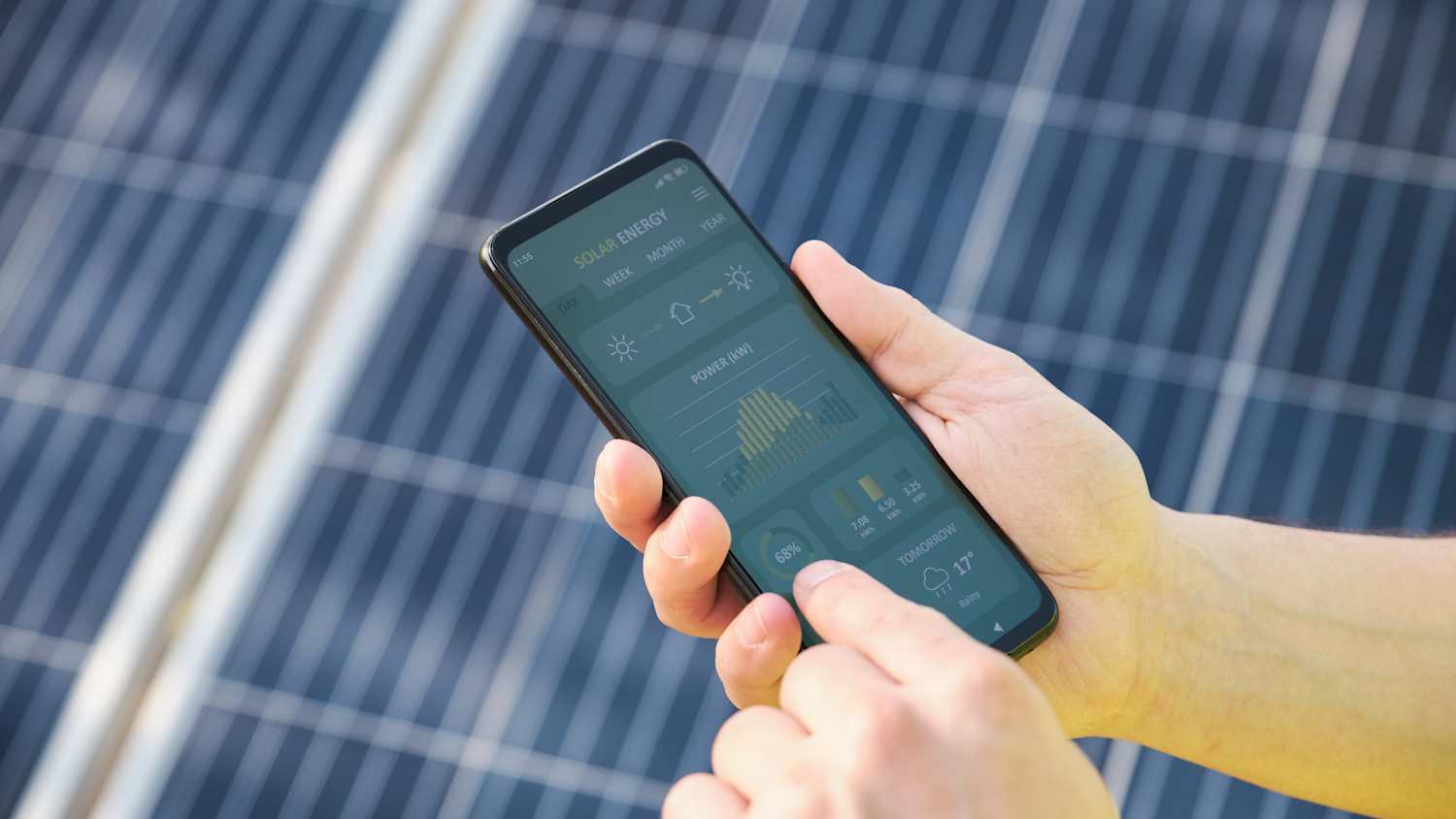 Ein Mann kontroliert mit seinem Handy seine Solaranlage auf dem Hausdach