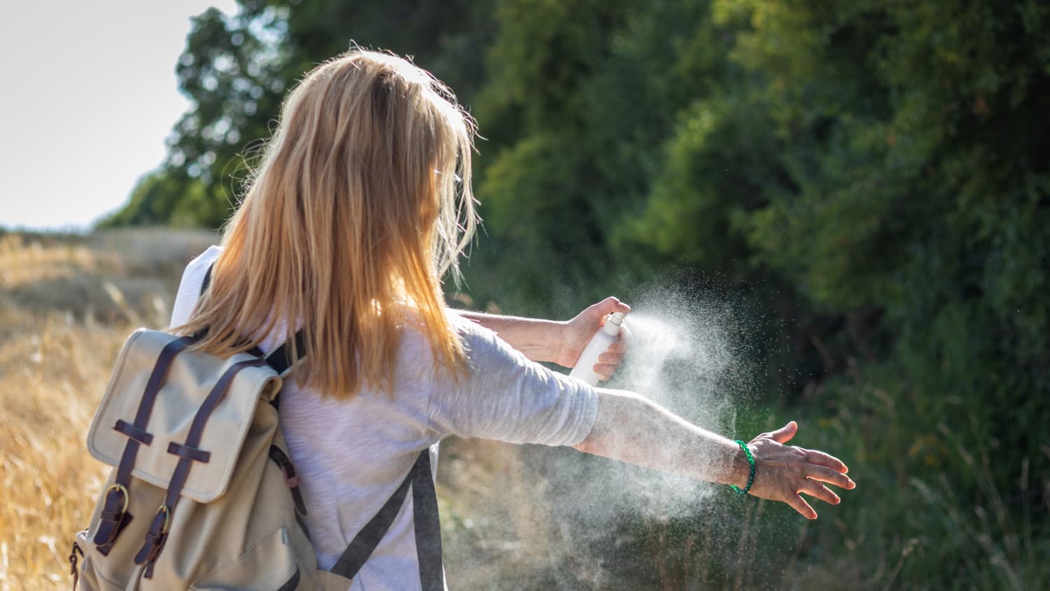Eine Frau sprüht Insektenschutzmittel auf ihren Arm