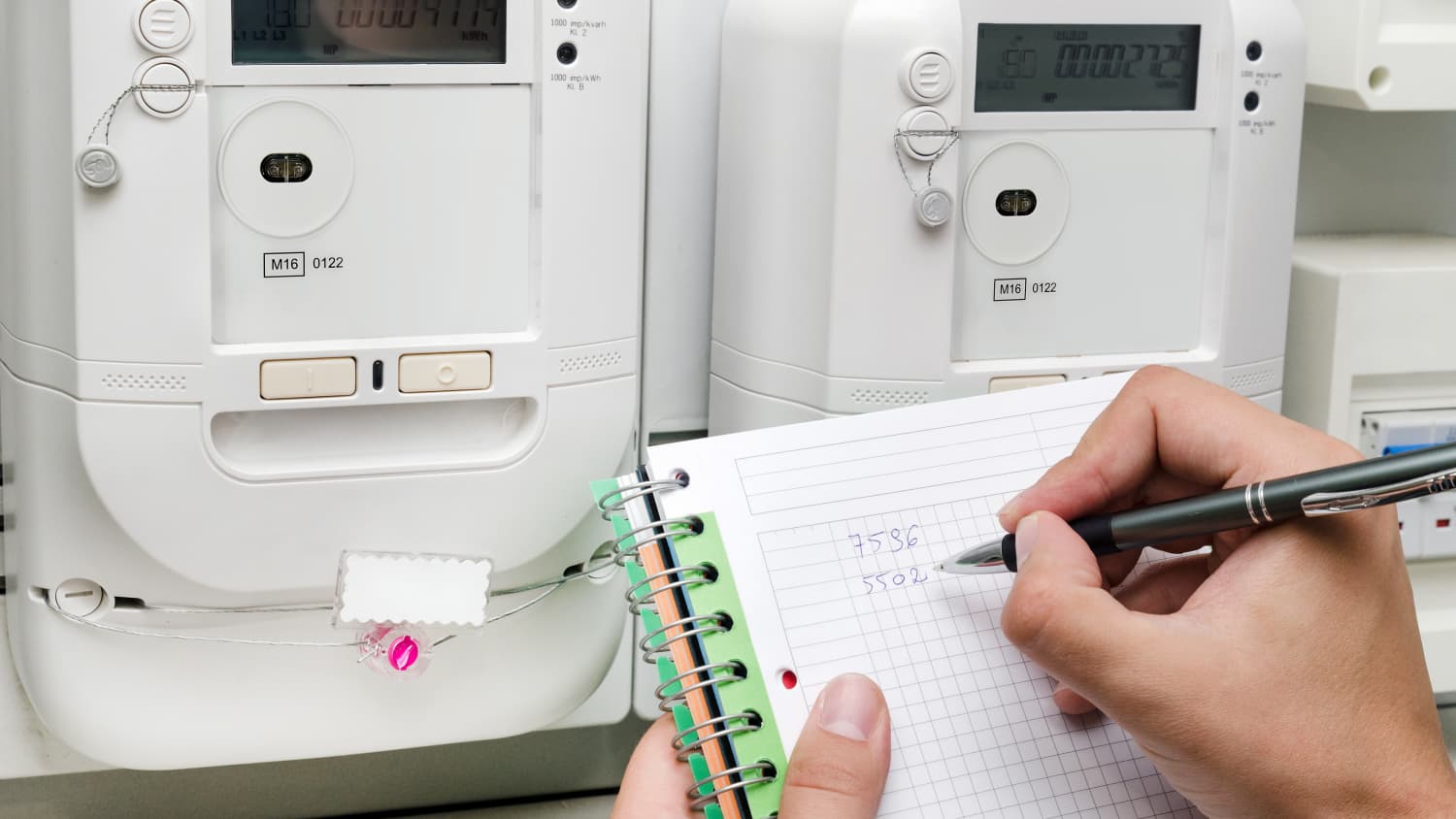 Person notiert den Stand der Zweirichtungszähler für den Stromverbrauch im Haus