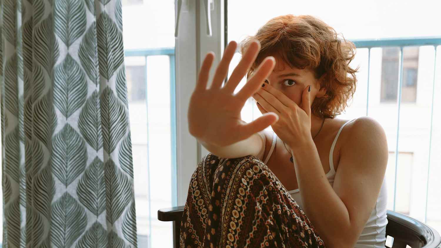Eine Frau sitzt ängstlich in ihrer Wohnung auf einem Stuhl