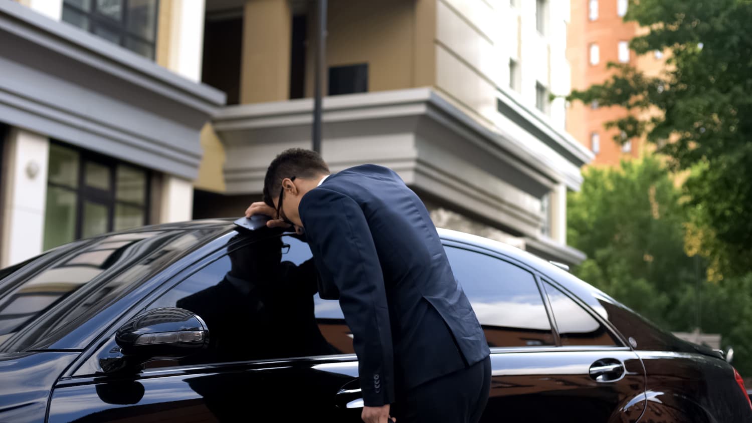 Ein Mann lehnt sich mit dem Kopf und dem Arm gegen sein AutoAuto