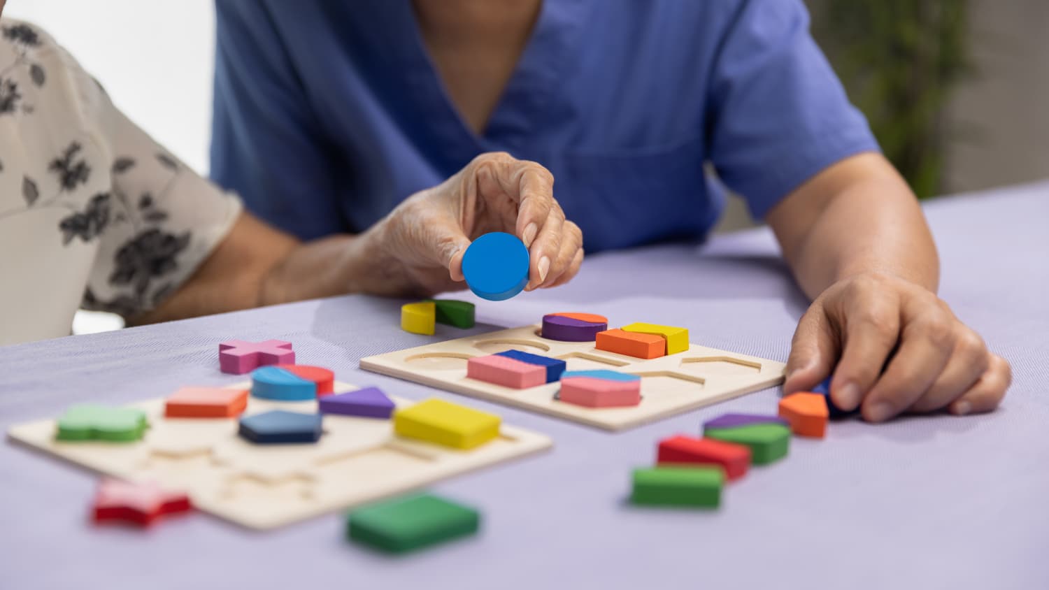 Eine Pflegekraft spielt mit einer alten Person ein Spiel zur Demenzvorbeugung