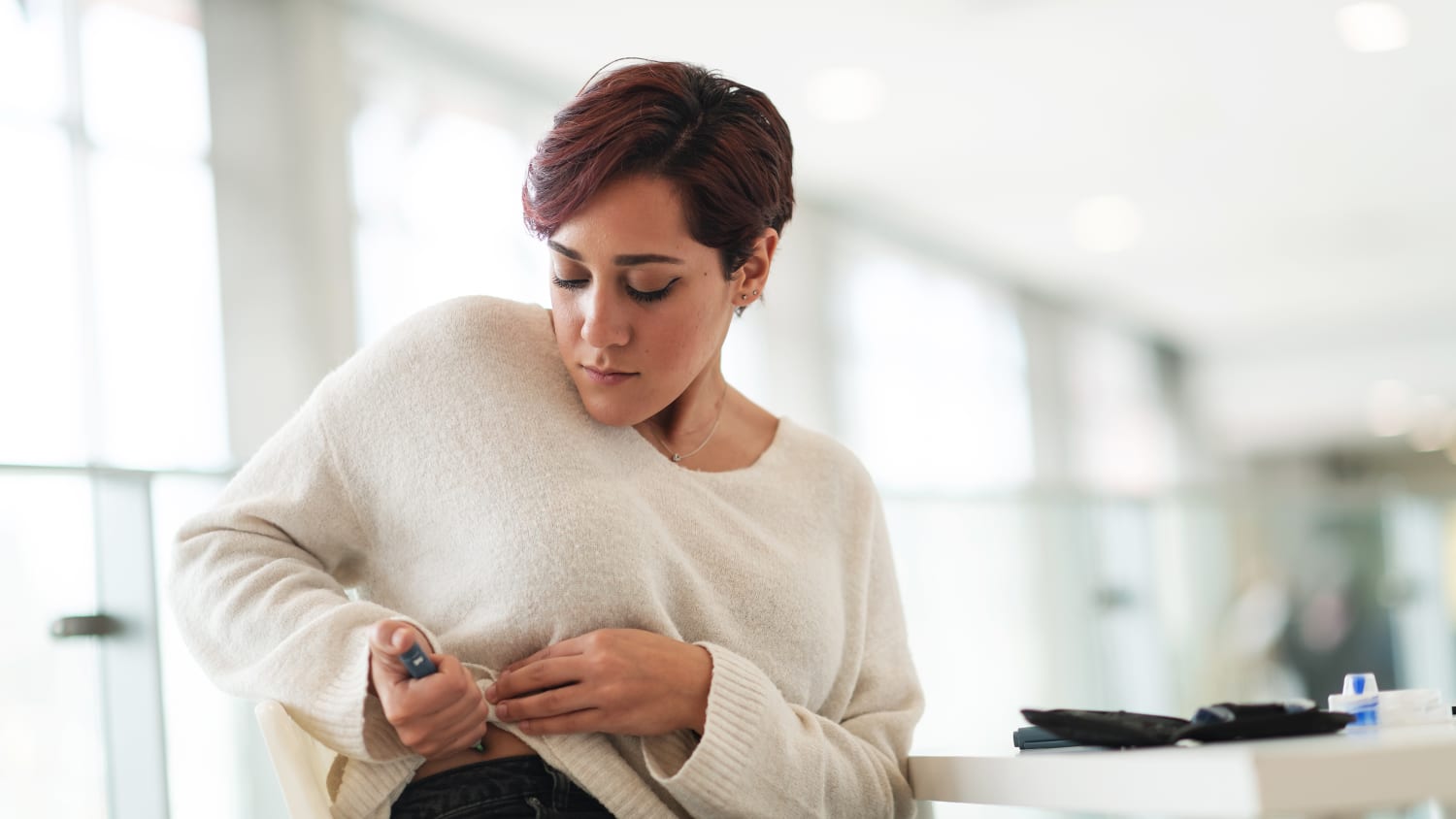 Eine junge Frau verabreicht sich in einem öffentlichen Raum eine Diabetes Spritze