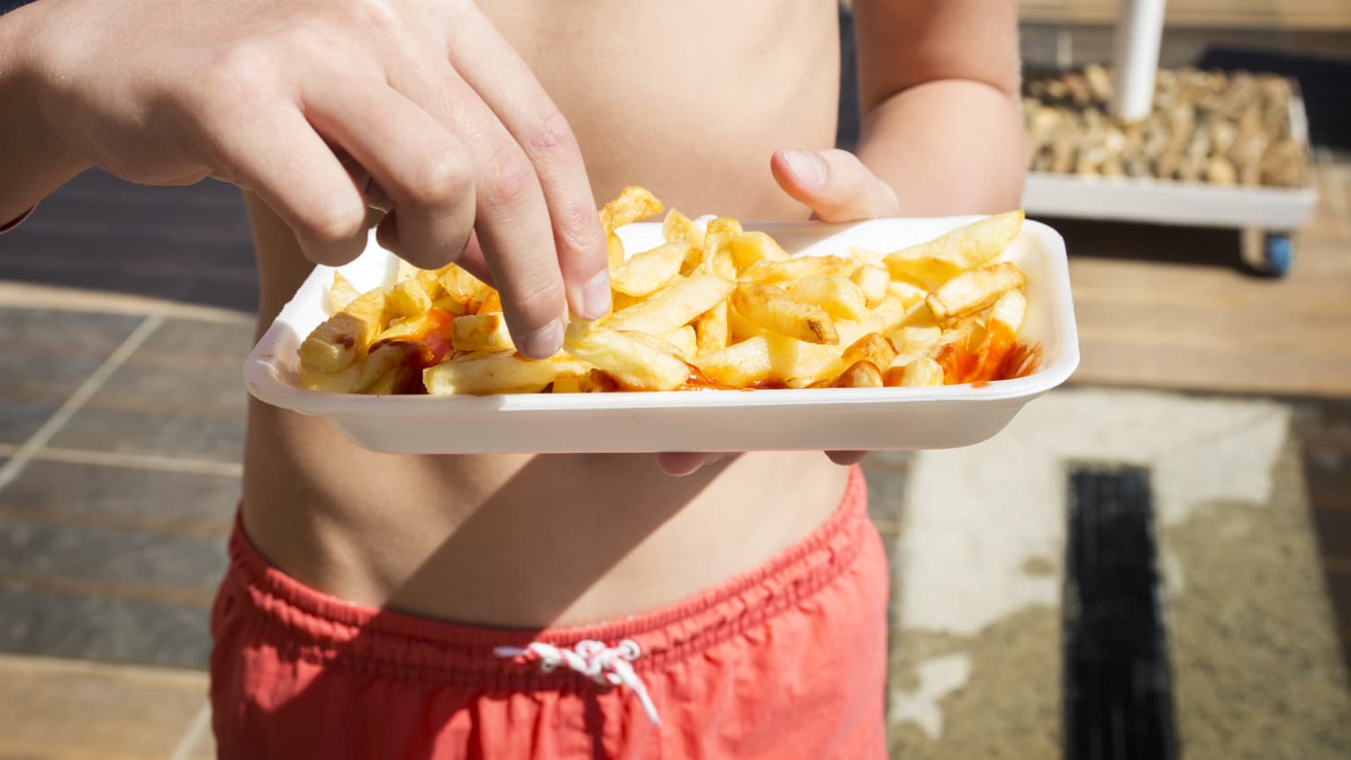 Ein Junge mit Pommes im Freibad