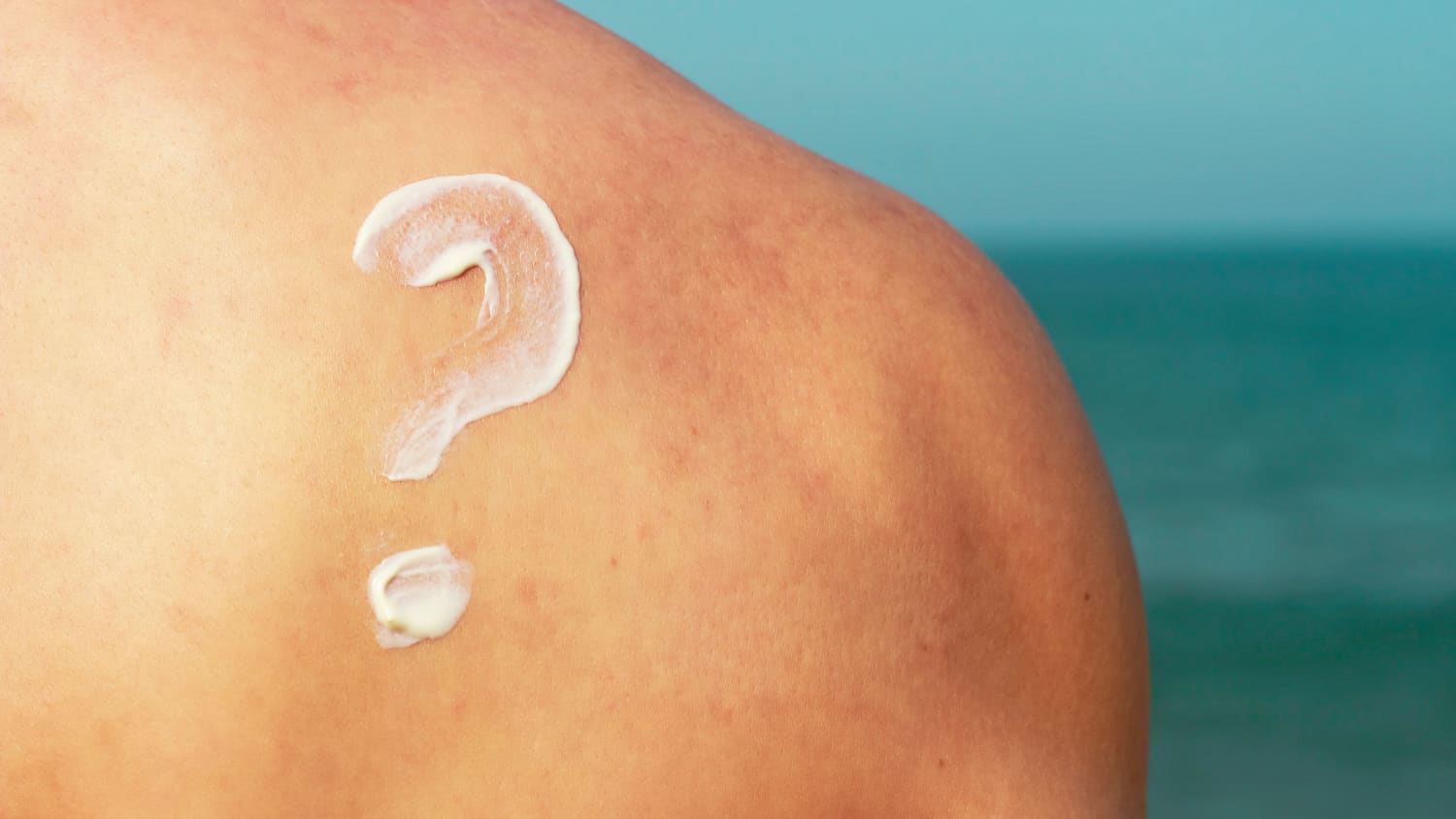 Ein aus Sonnencreme geschmiertes Fragenzeichen ist auf der Schulter eines Mannes