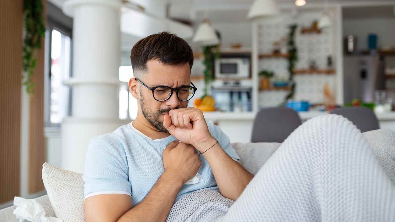 Ein Mann liegt krank auf dem Sofa