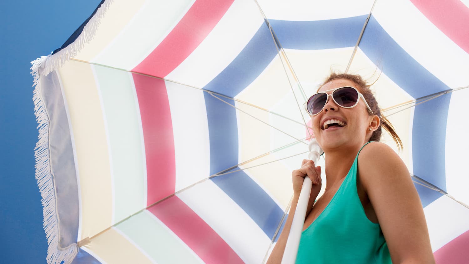 Eine junge Frau hält einen Sonnenschirm und ist glücklich