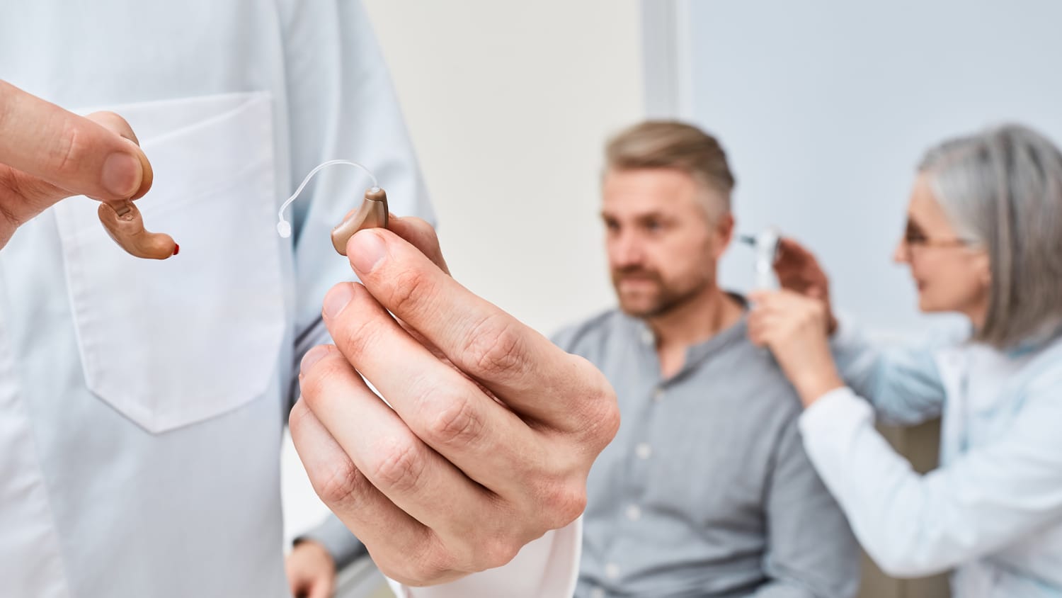 Audioprosthetis wählt nach der Höruntersuchung für hörgeschädigte Patienten zwischen Im-Ohr- und Hinter-dem-Ohr-Hörgeräten zur Behandlung von Taubheit