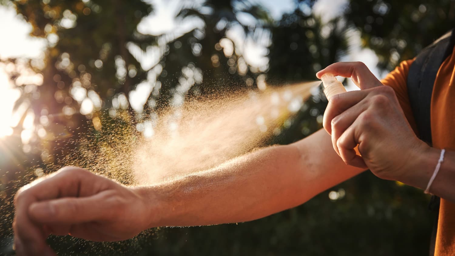 Ein Mann besprüht seinen Arm mit Mückenschutz