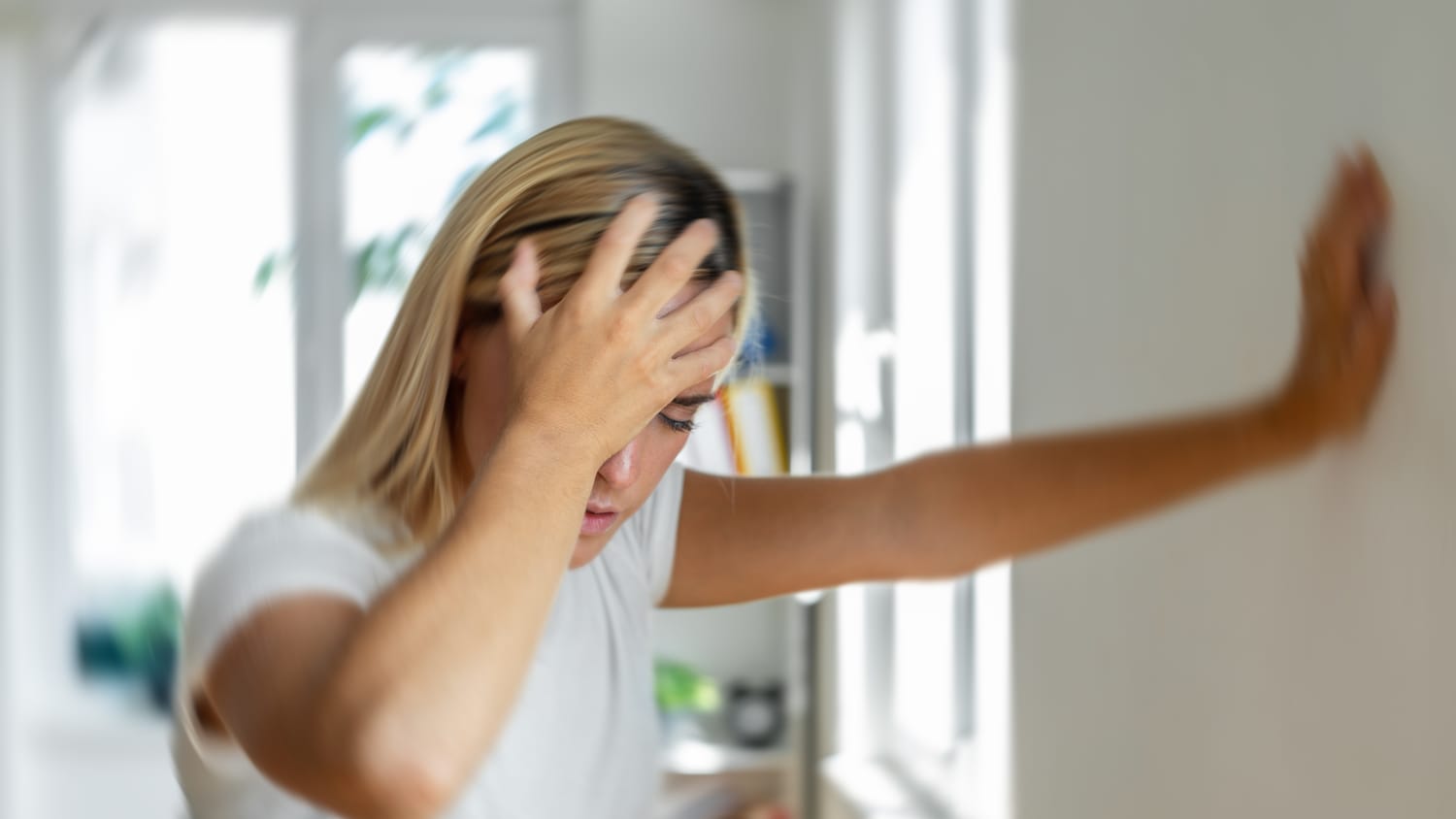 Eine Frau stützt sich mit Schwindel an einer Wand ab