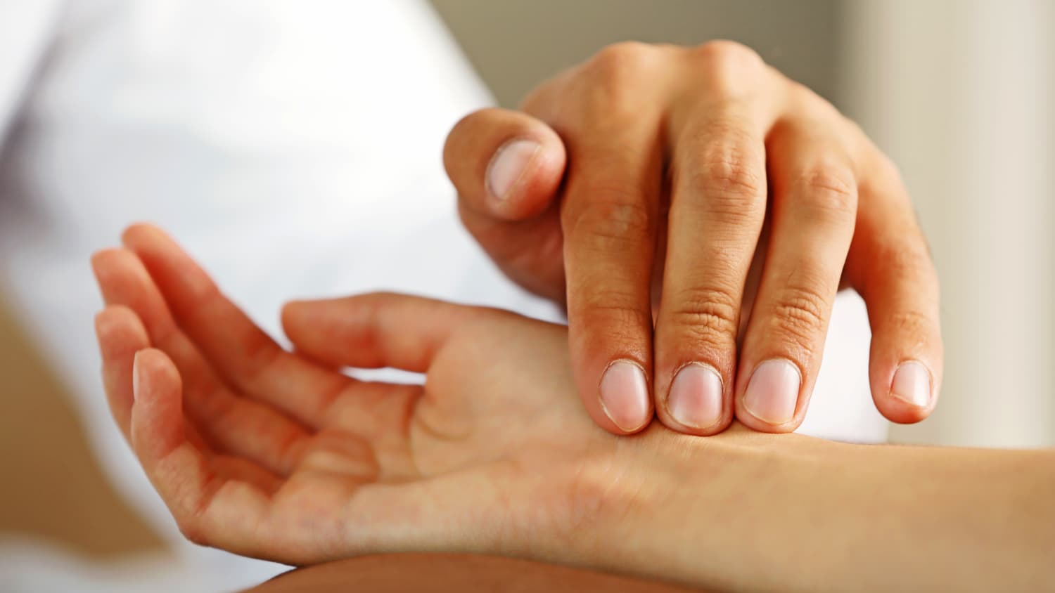 ein Arzt misst den Puls einer Patientin