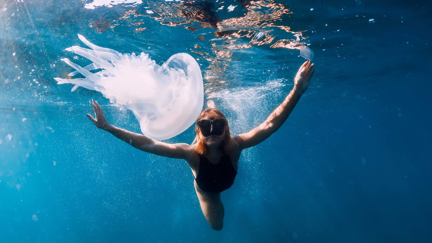 Frau unter Wasser mit Quallen im blauen Ozean