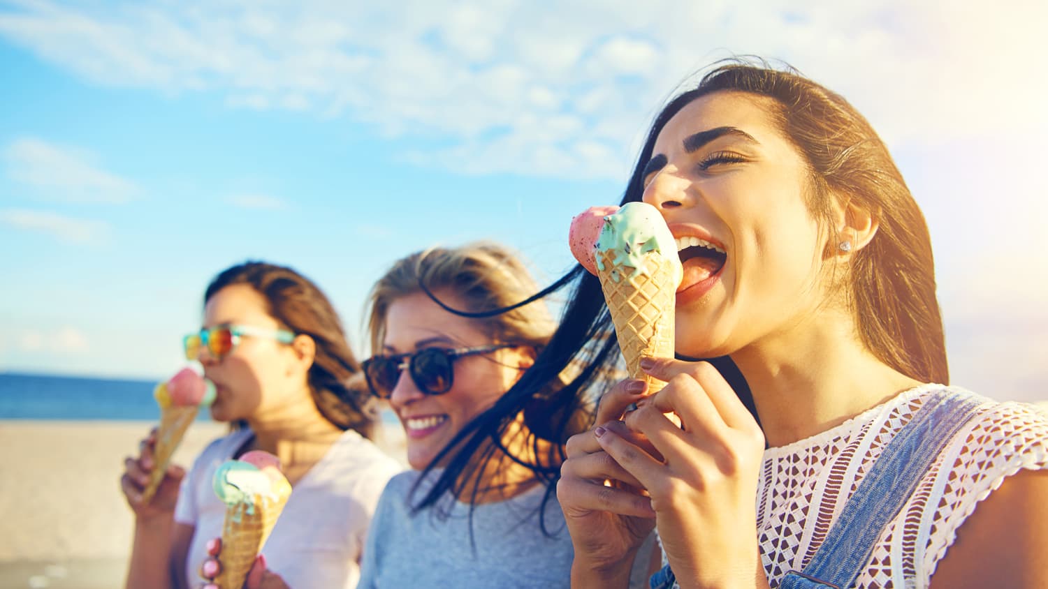 Drei junge Frauen essen Eis am Meer