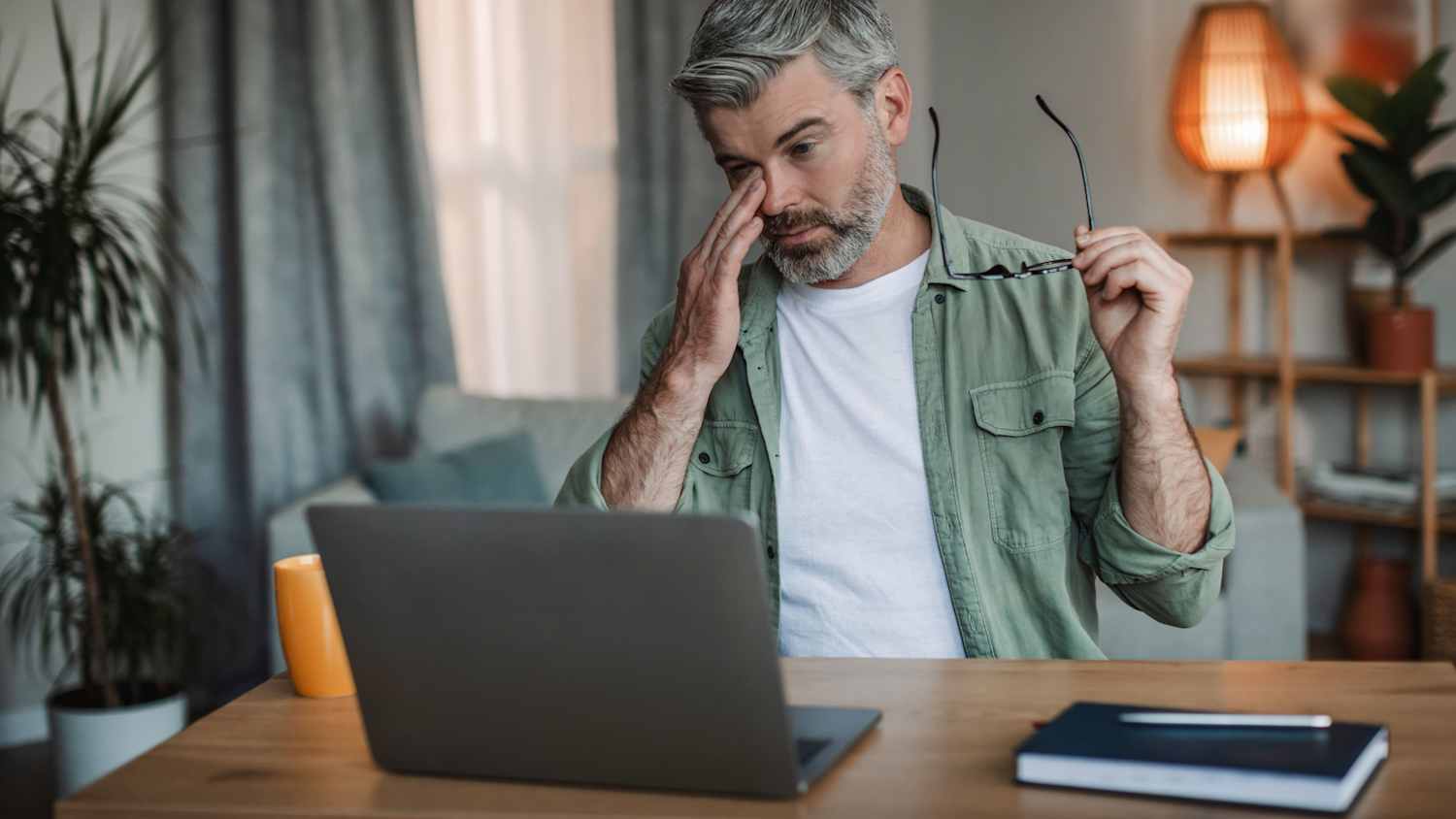 Ein Mann sitzt vor seinem Computer und reibt sich die Augen
