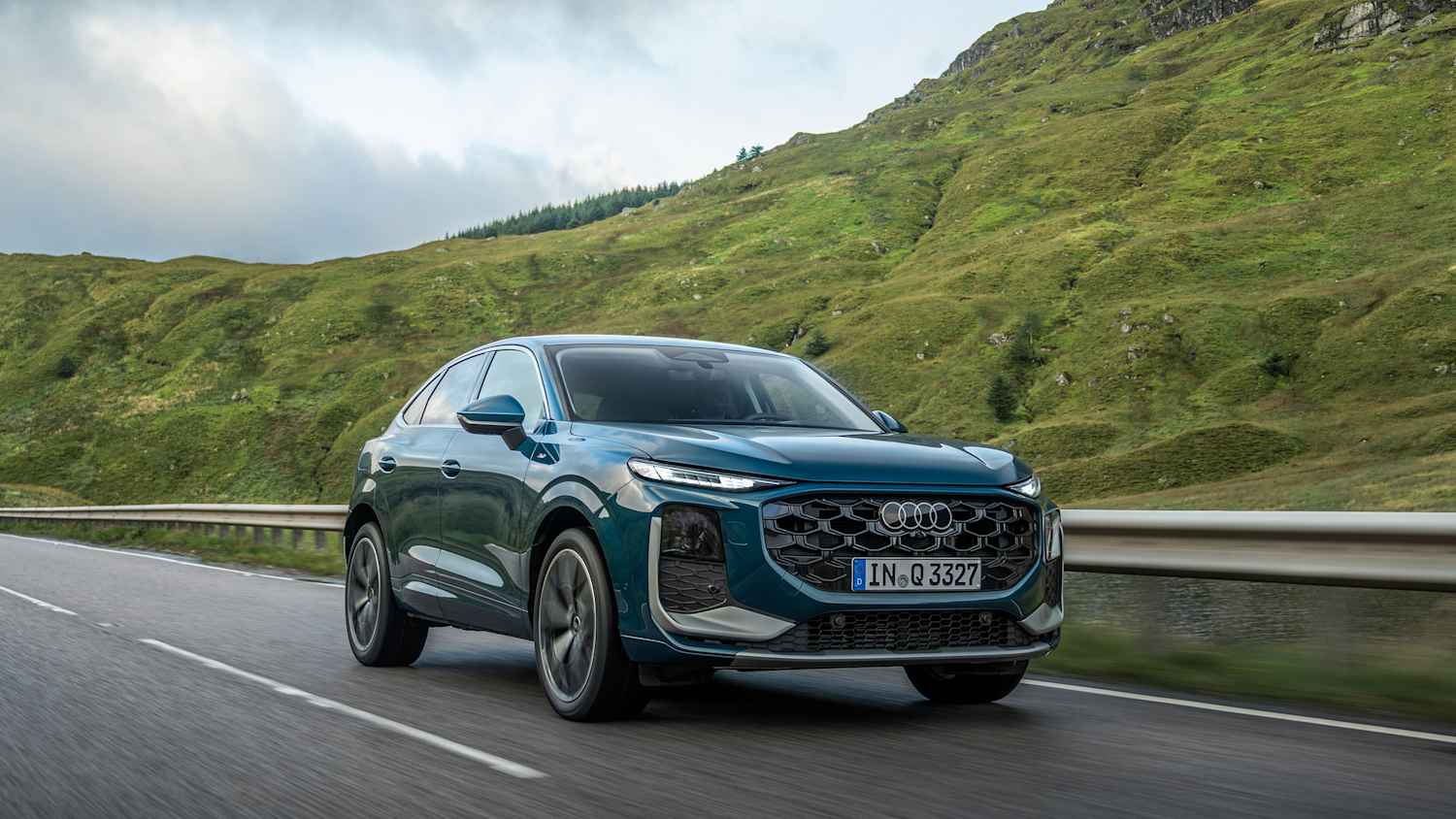 Aufnahme des blauen fahrenden Audi Q3 auf einer Landstraße