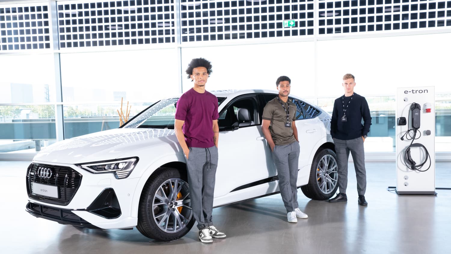 Leroy Sané, Serge Gnabry, Joshua Kimmich stehen vor einem Audi E-Tron