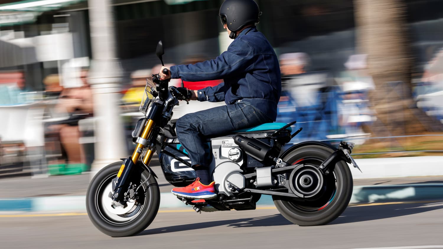 Seirtenansicht einer fahrenden BMW CE 02 auf der ein Mann sitzt