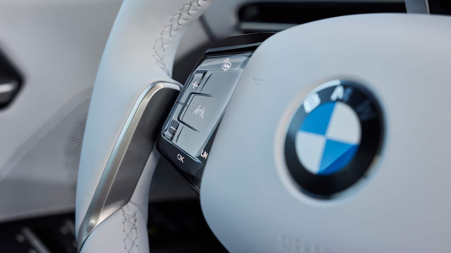 Detailaufnahme des Lenkrads im BMW iX3 mit sichtbaren Bedienelementen.