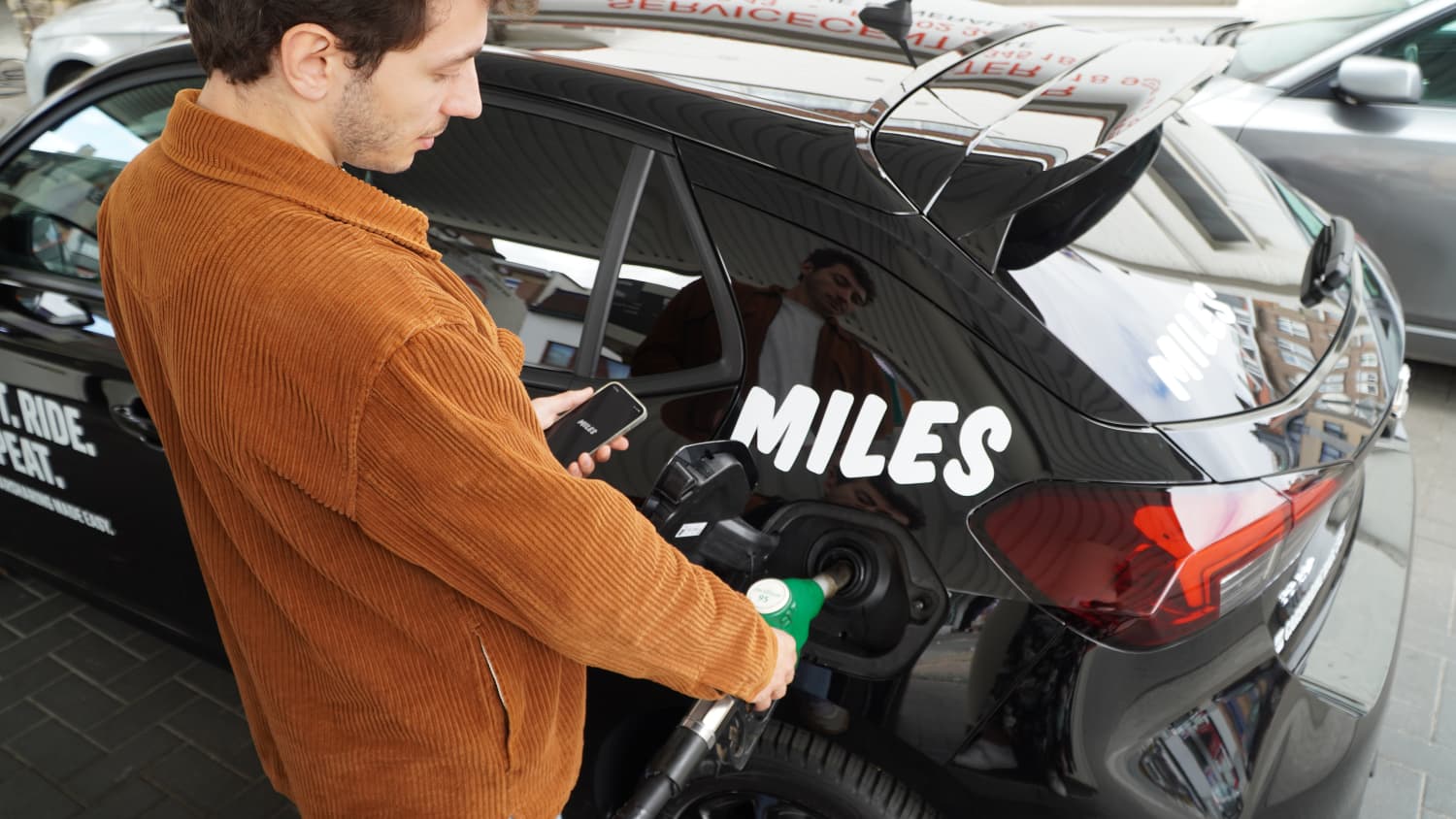 Ein Mann tankt ein Miles Carsharing Auto