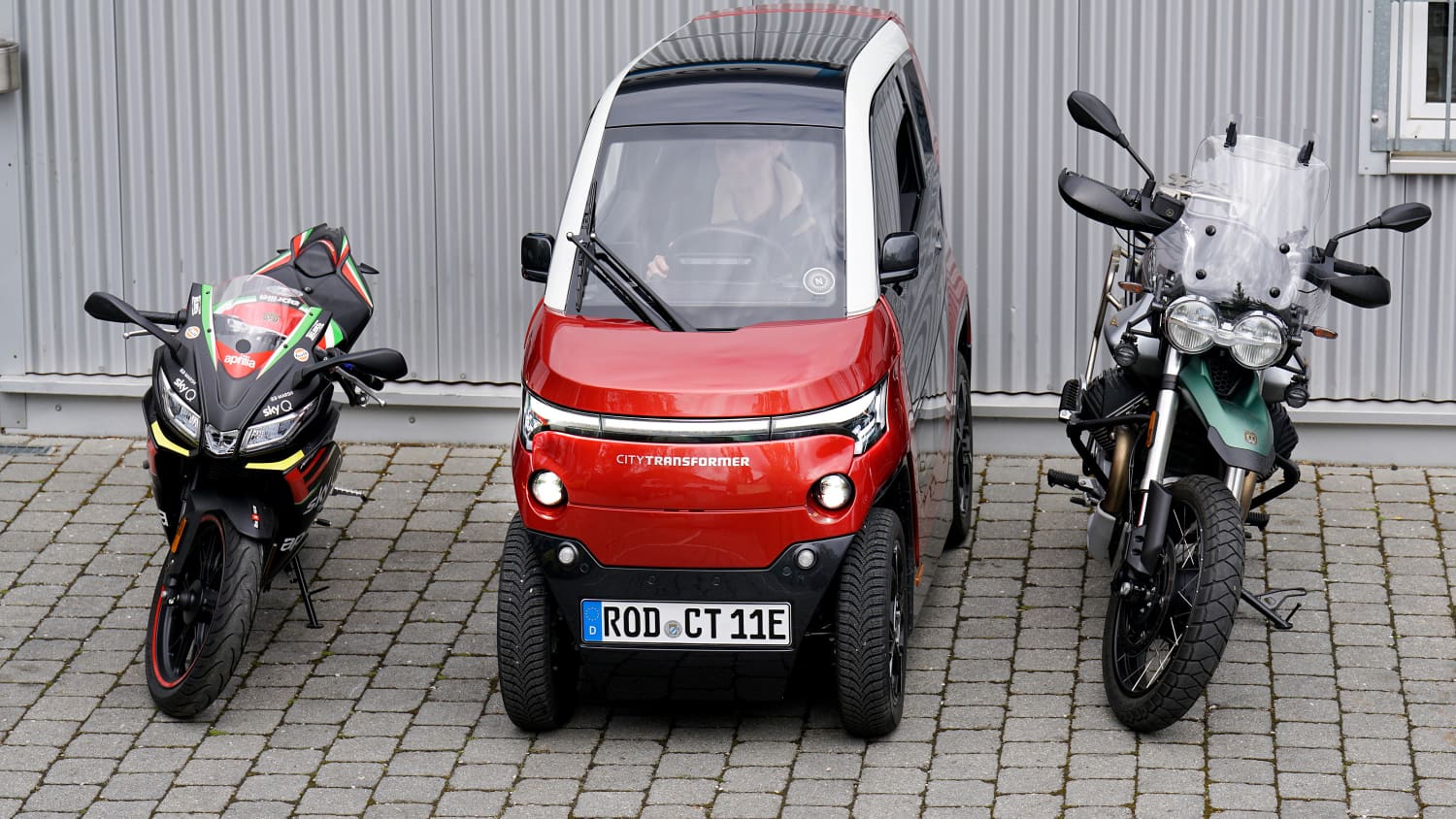 Ein City Transformer Auto parkt zwischen zwei Motorraedern