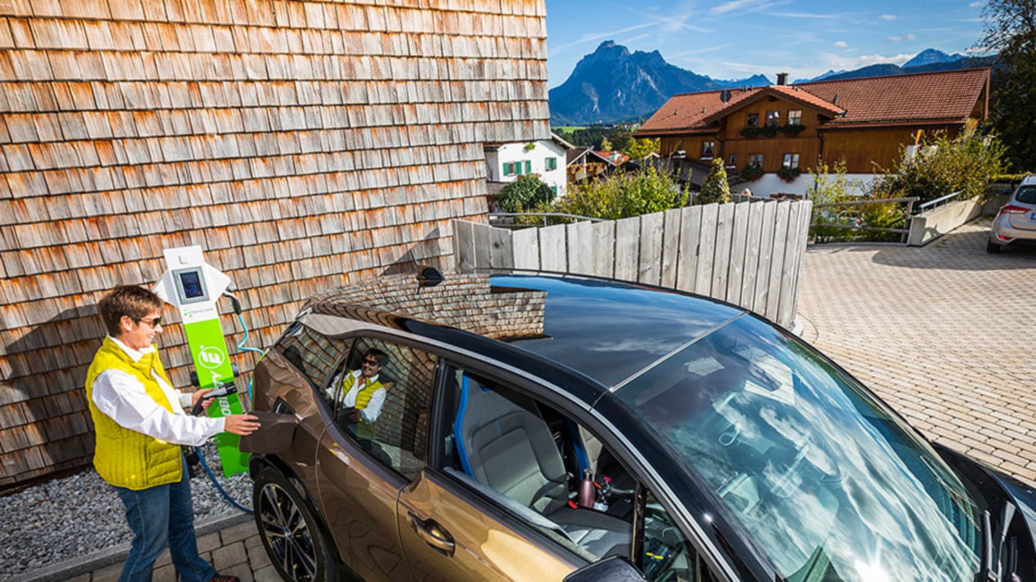 Eine Frau läd ein E-Auto in einer Einfahrt