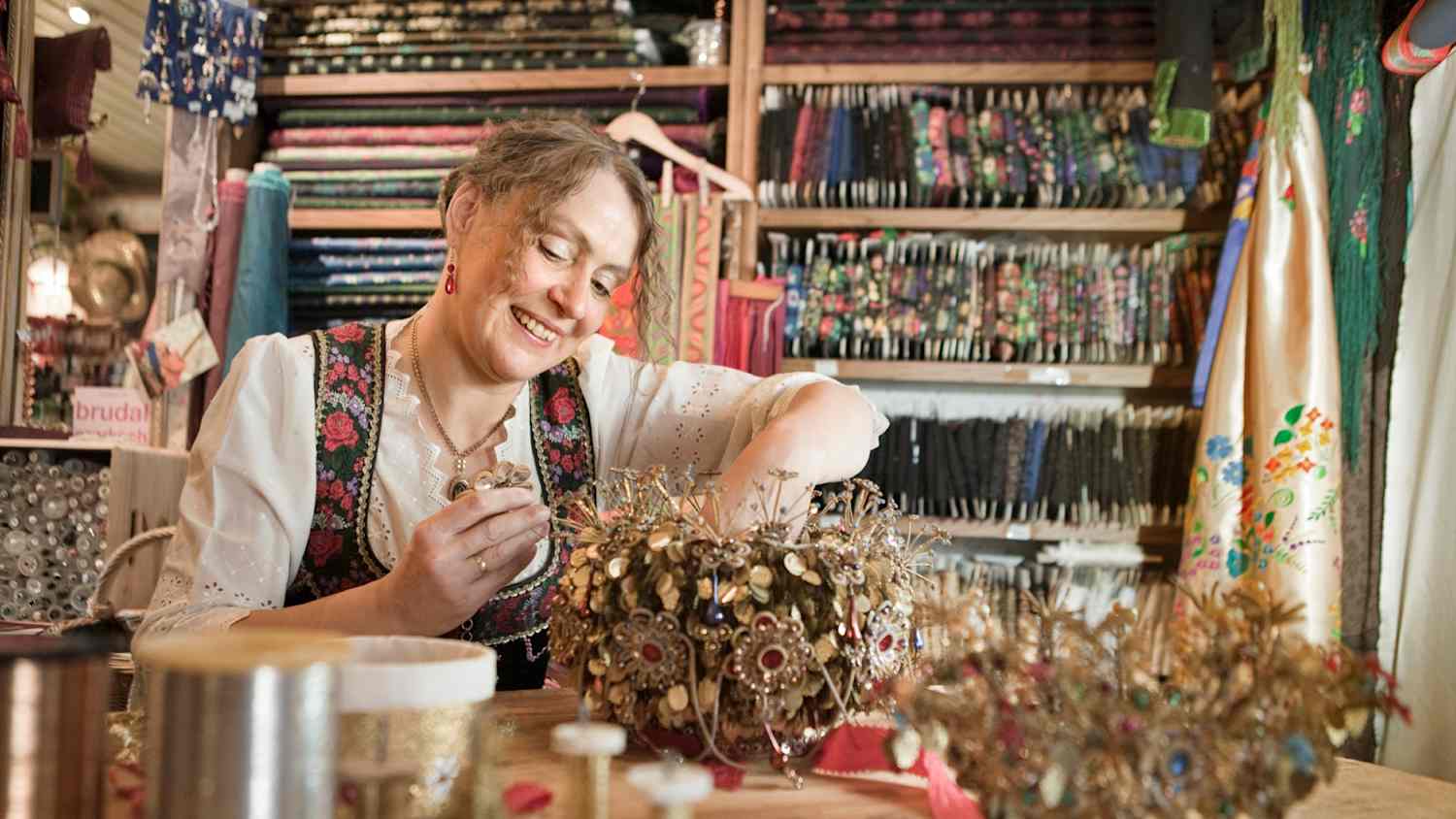 Eine Frau im Dirndl macht Flitterkränze