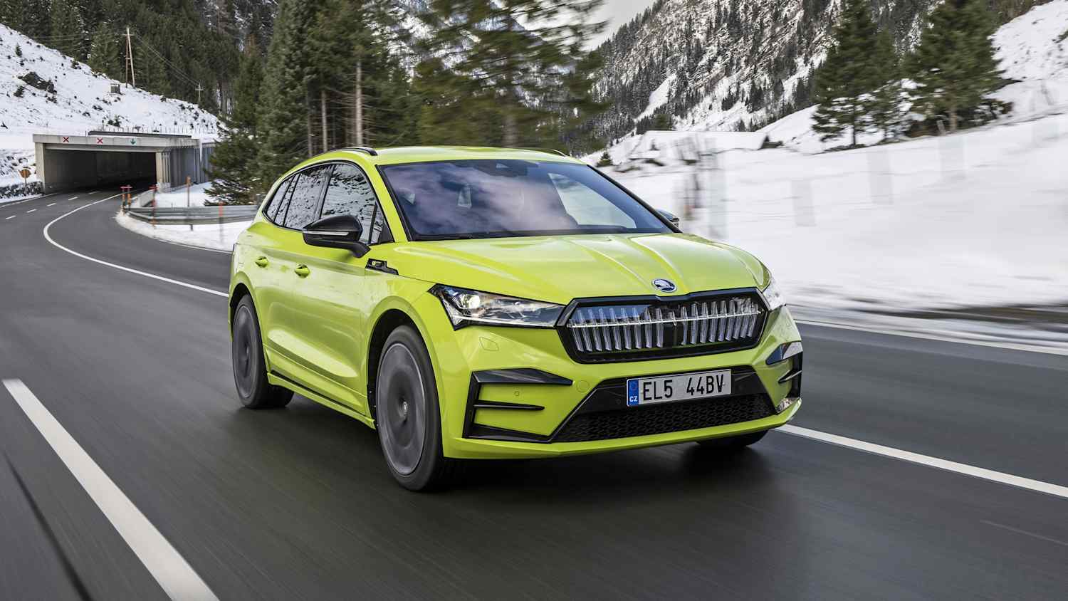Front und Seitenansicht eines fahrenden Skoda Enyaq in einer Winterlandschaft