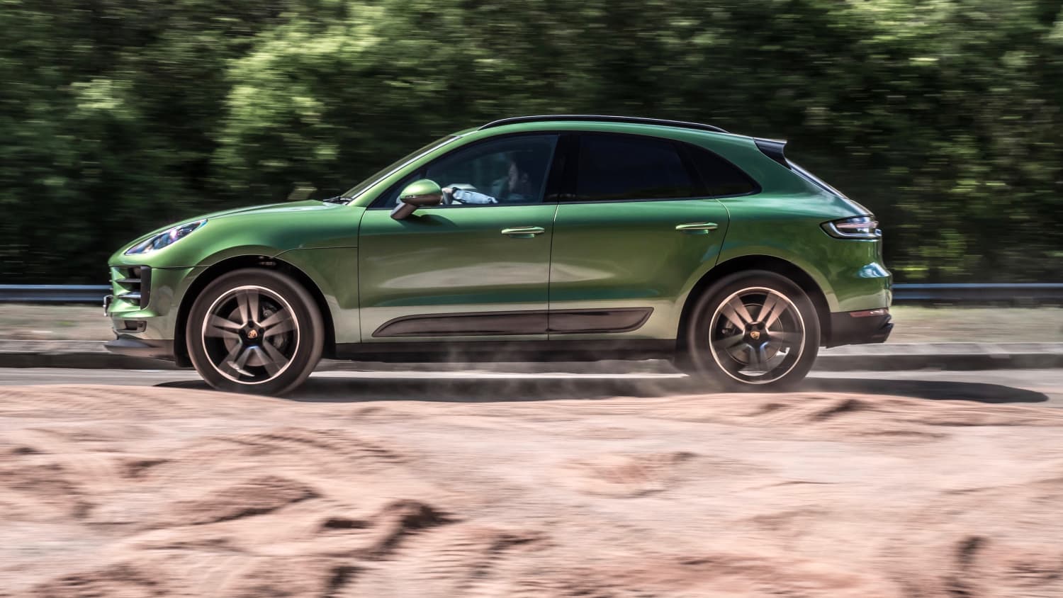Seitenansicht eines grünen fahrenden Porsche Macan S