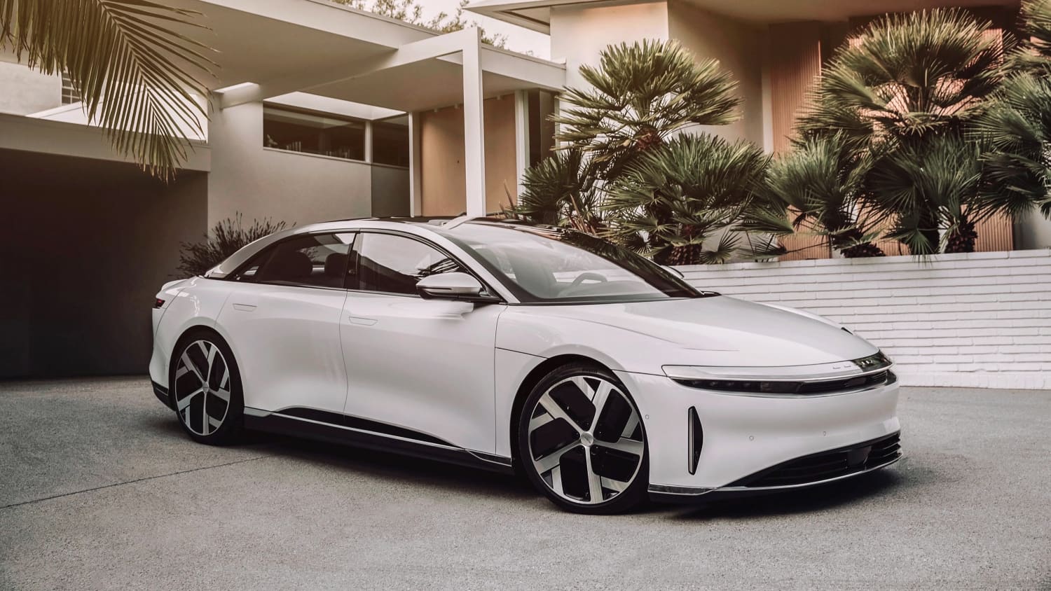 Ein weißer Lucid Air steht vor einer Hausgarage
