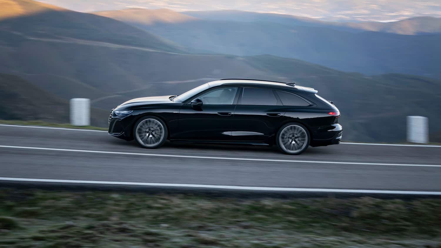 Der neue Audi Avant A6 fahrend seitlich auf einer Straße fotografiert