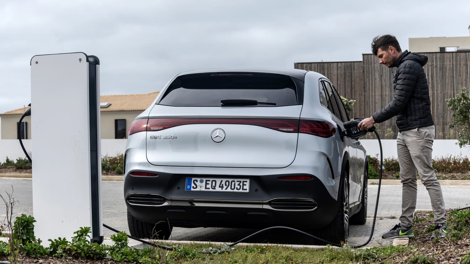 Ein Mann lädt einen Mercedes EQE SUV an einer Ladesäule