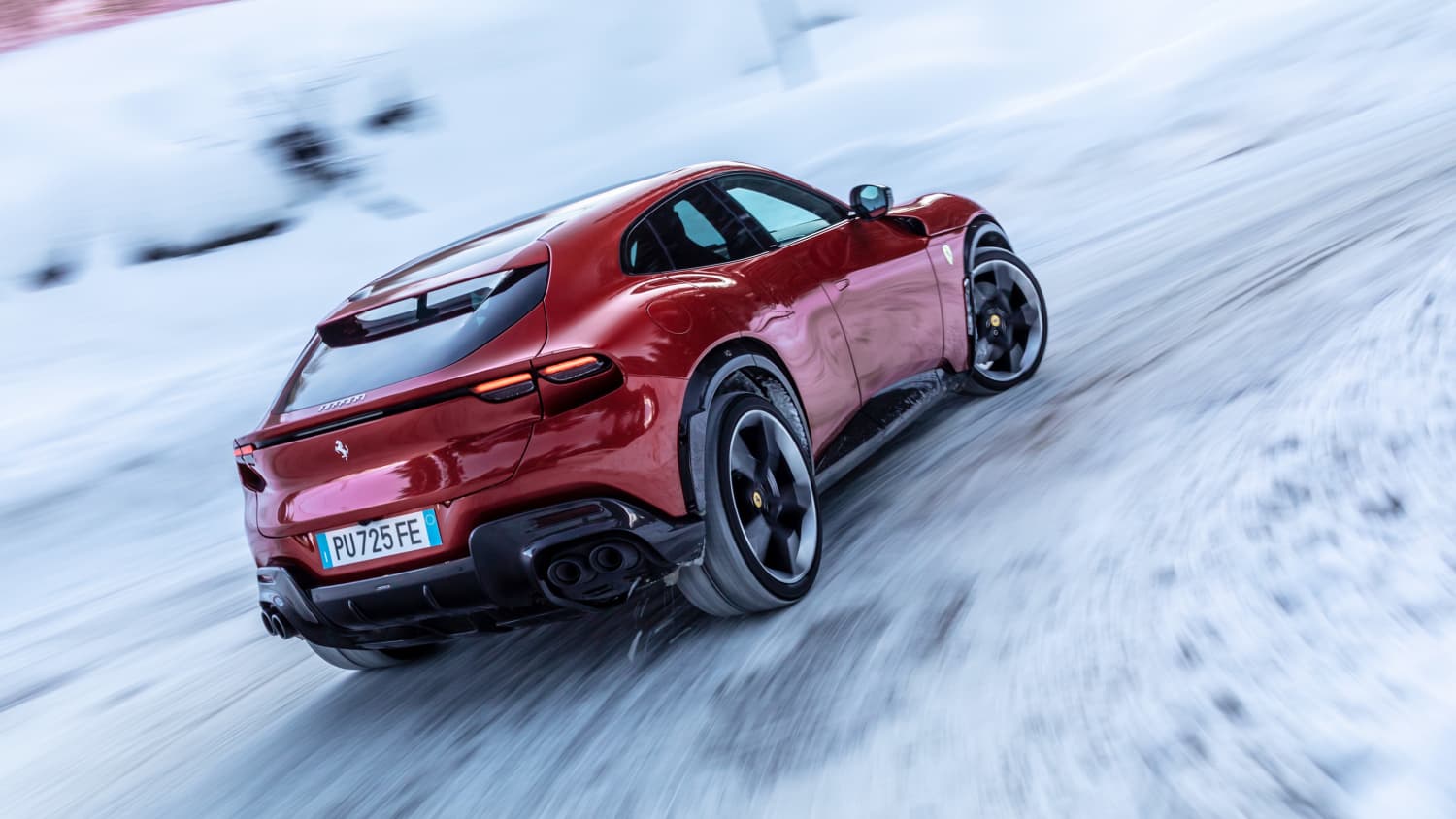 Seitliche Rueckansicht eines fahrenden Ferrari SUV's Purosangue im Schnee