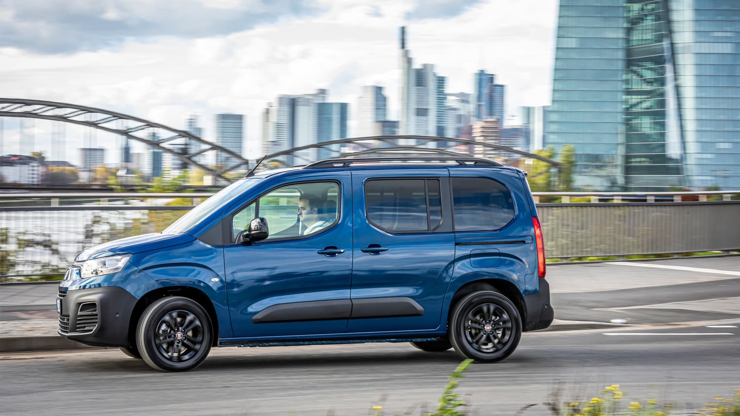 Der neue Fiat e-Doblo in dunkelblau während der Fahrt durch die Stadt