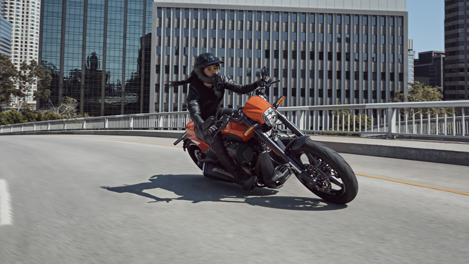 Eine Harley Davidson fährt auf einer Strasse, im Hintergrund stehen moderne Häuser