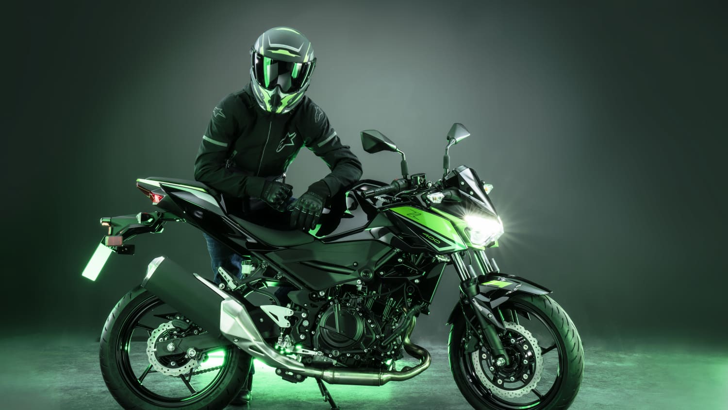 Ein Motorradfahrer auf der neuen Kawasaki Z 400 im Studio, grün beleuchtet