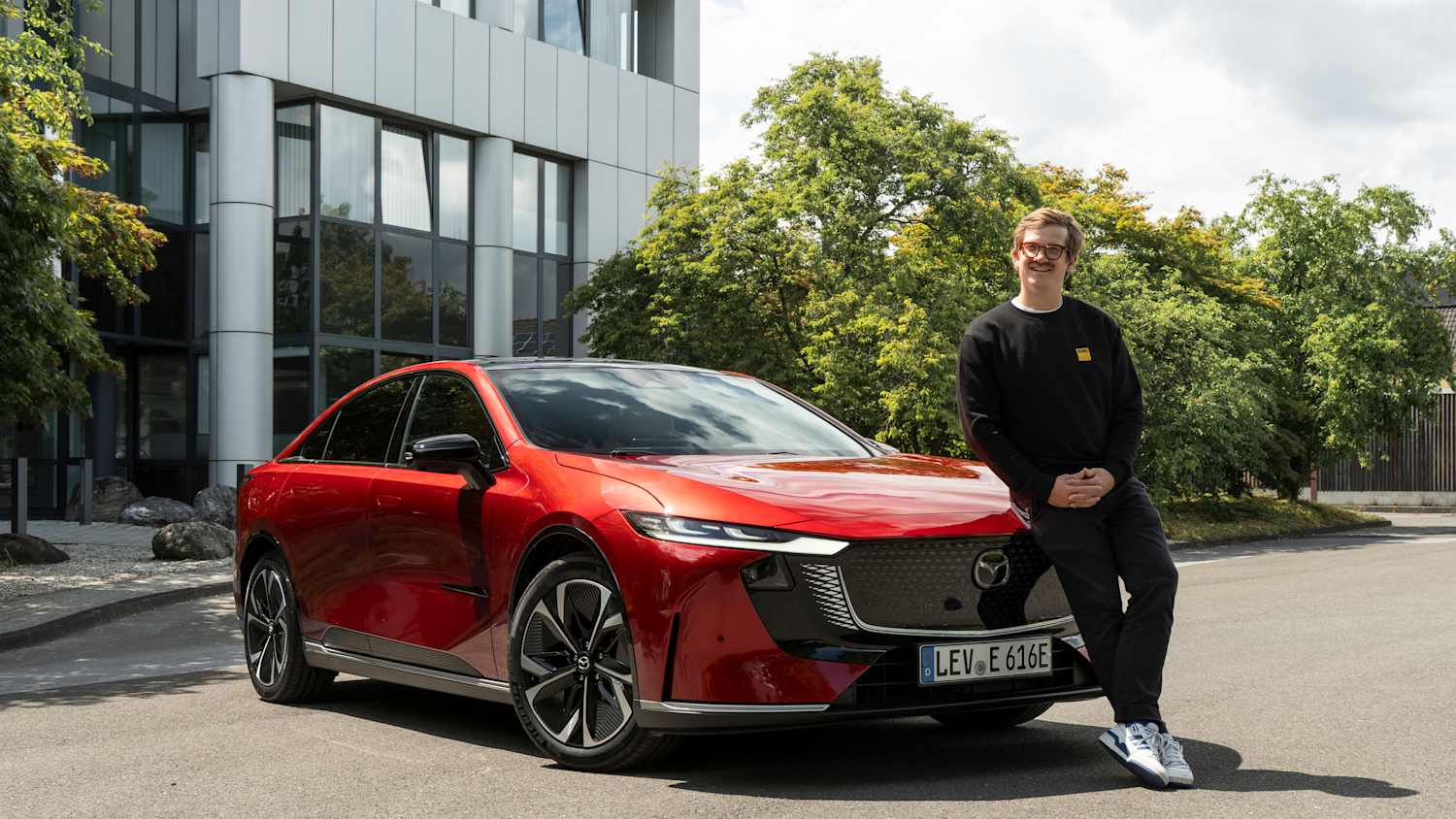 Der ADAC Redakteur Andreas Huber lehnt auf der Motorhaube des Mazda 6e