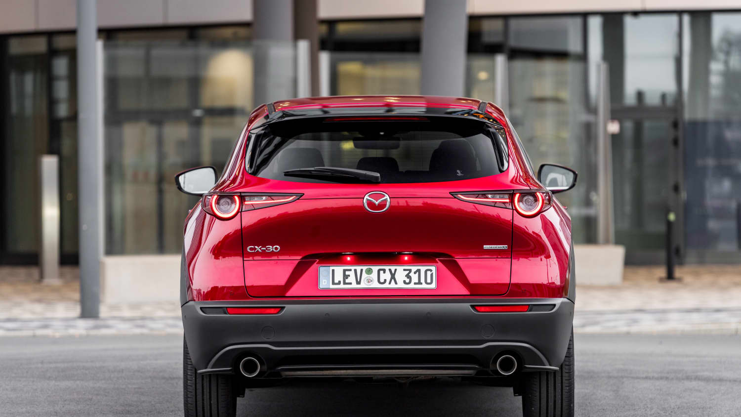 Ein roter Mazda CX-30 von hinten parkend vor einem Gebäude