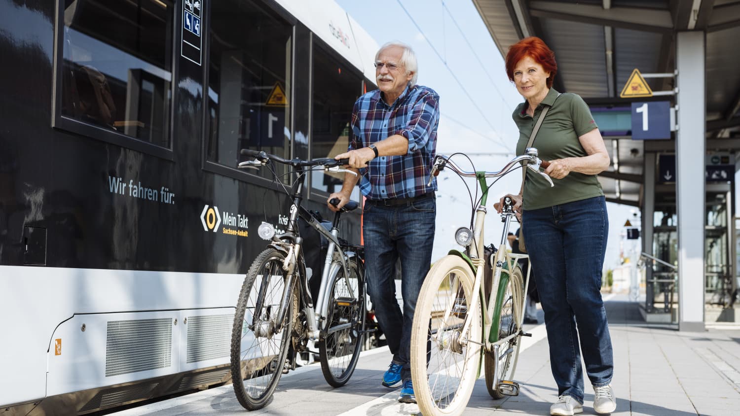 Älteres Ehepaar bei der Fahrrad-Mitnahme in Sachsen-Anhalt vor einem Zug mit dem mit dem Kennzeichen "Mein Takt"