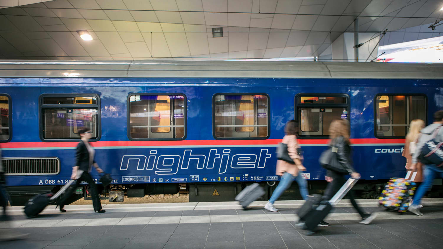 Passagiere laufen an einem Bahnhof an einem Nightjet Zug entlang