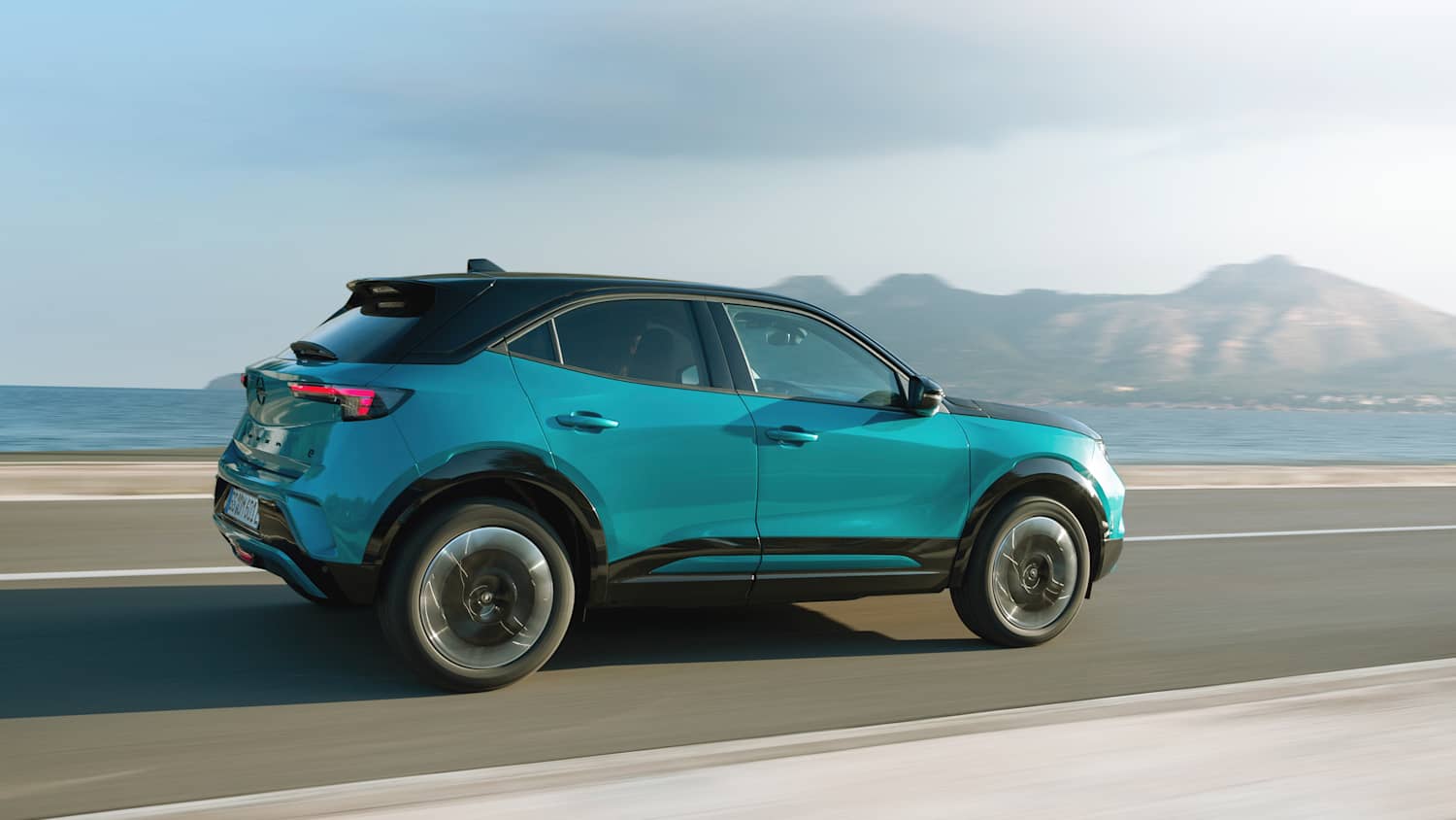 Der neue Opel Mokka Electric waerend der Fahrt seitlich fotografiert