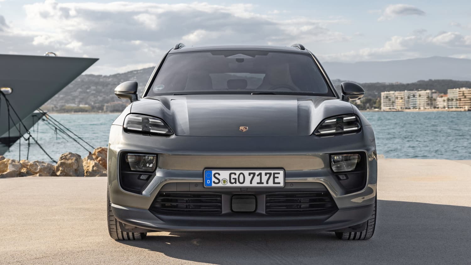 Ein Porsche Macan E direkt von Vorne steht an einem Hafenbecken
