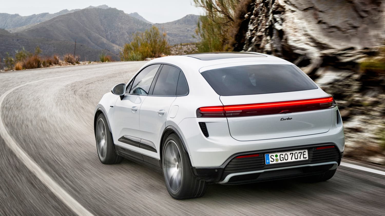 Der Porsche Macan E Turbo 5 fahrend von hinten