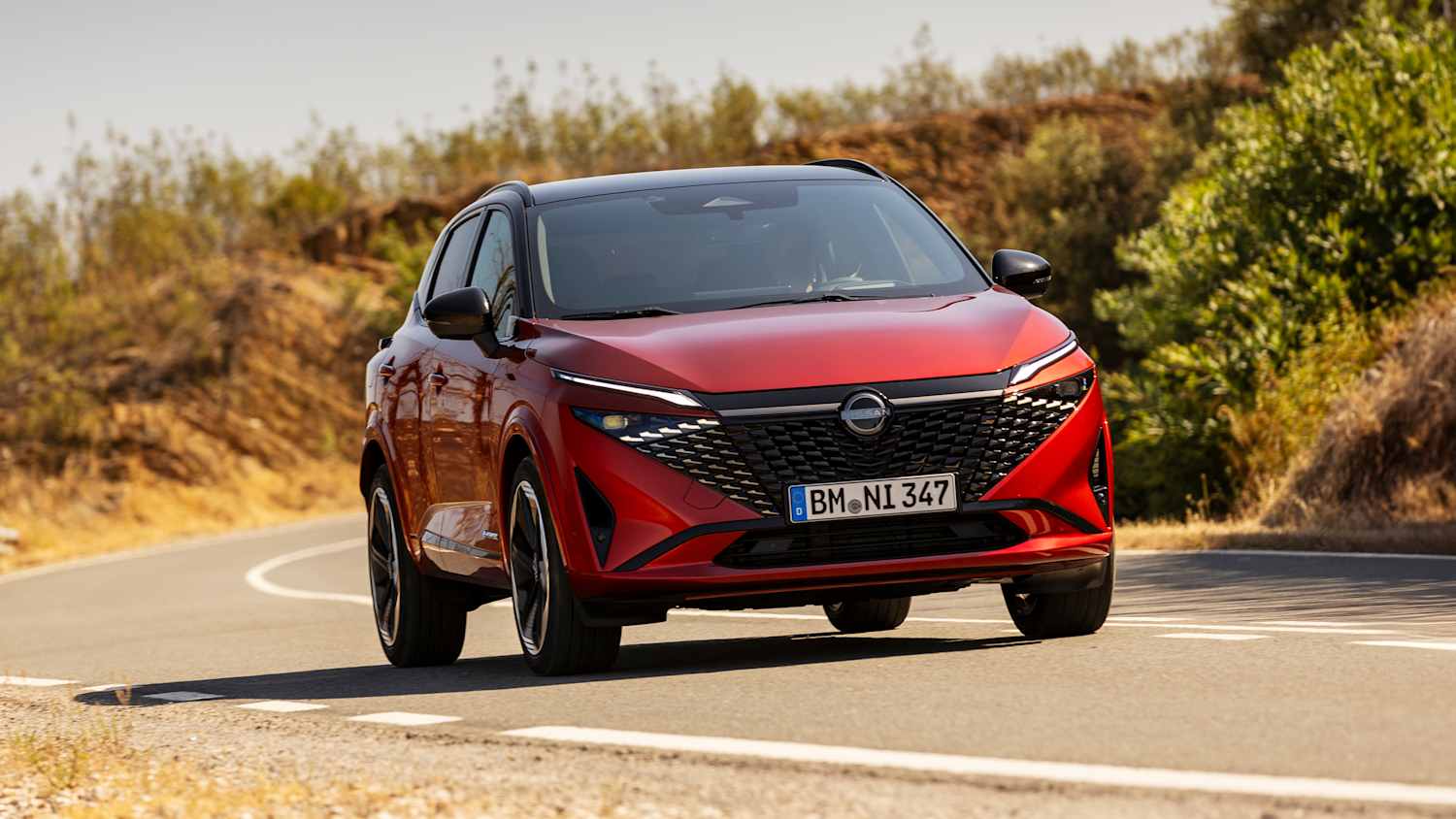 Aufnahmen des fahrenden Nissan Qashqai auf einer Landstraße bei Sonnenuntergang